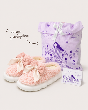 Pantuflas Cuco moño color rosa junto a su guardapolvos lila ilustrado y la tarjeta de Cuco